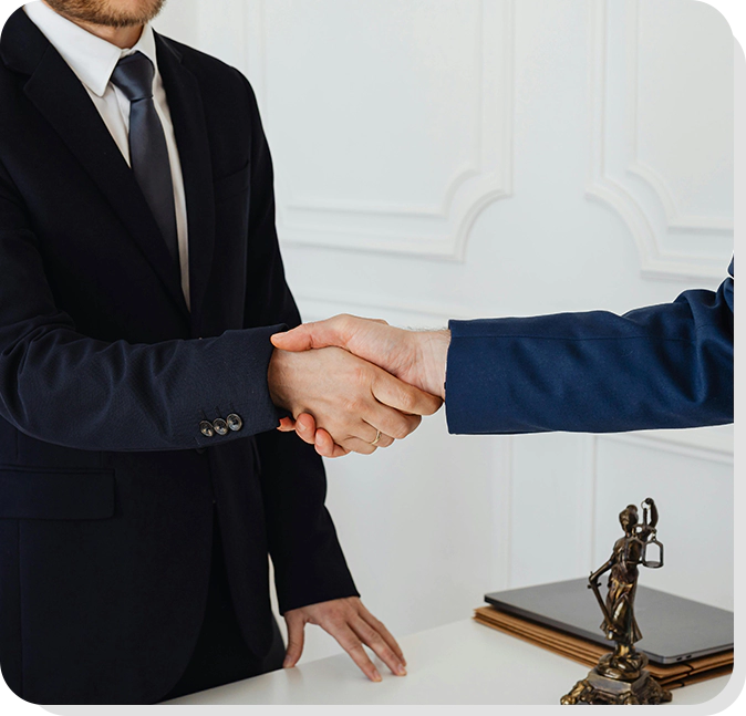 Two men shaking hands over a table with a statue of a woman.